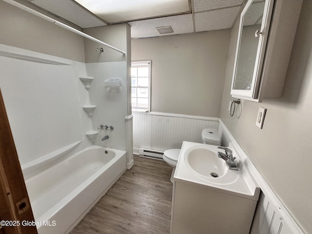 bathroom with toilet, wainscoting, wood finished floors, a paneled ceiling, and a baseboard radiator