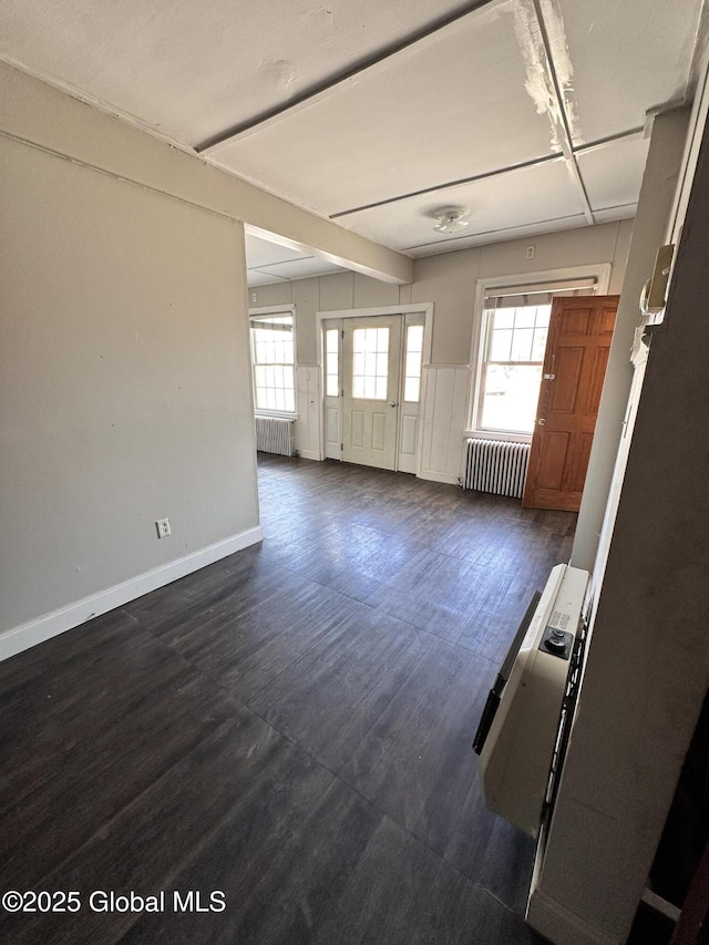 interior space with a wealth of natural light, radiator heating unit, and dark wood-type flooring