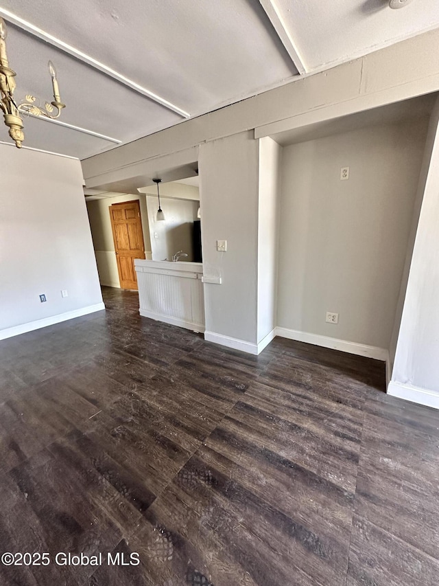 unfurnished living room featuring dark wood-style floors, baseboards, and a sink