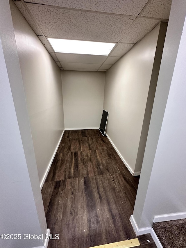 empty room with a drop ceiling, baseboards, and wood finished floors