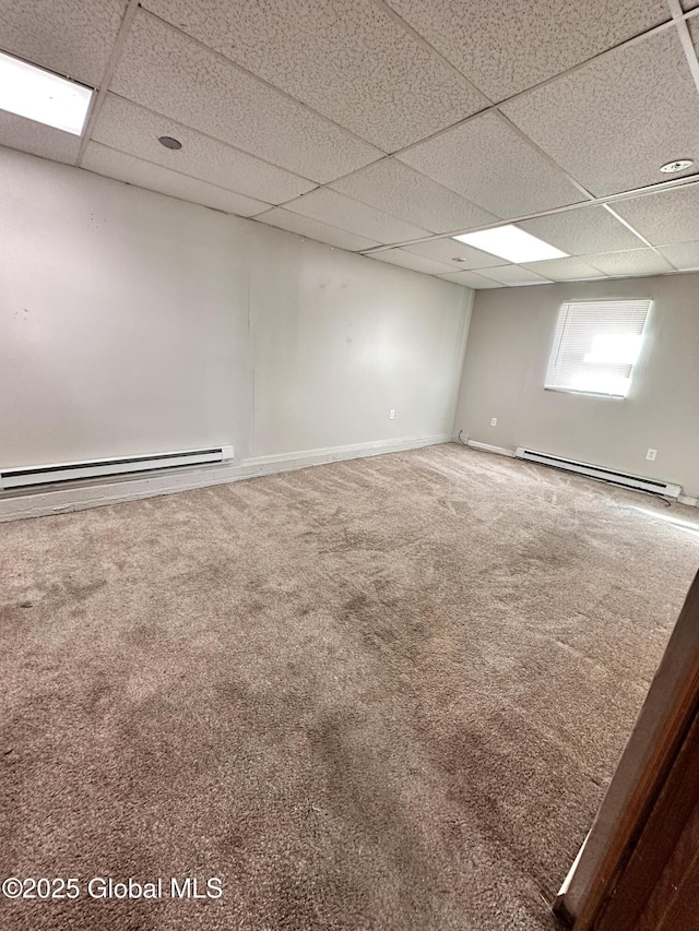 carpeted spare room featuring baseboard heating, baseboards, and a drop ceiling