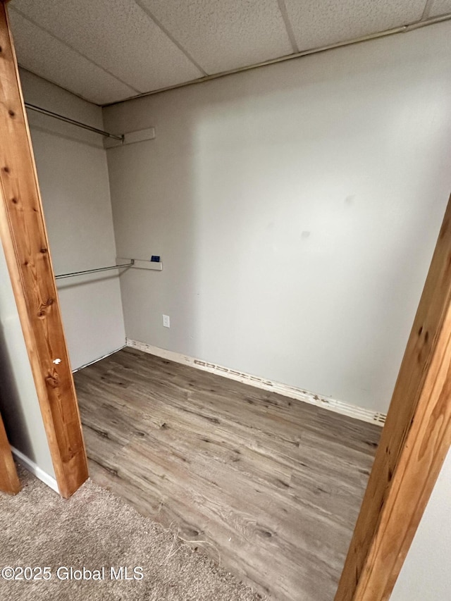 finished basement with baseboards, a paneled ceiling, and wood finished floors