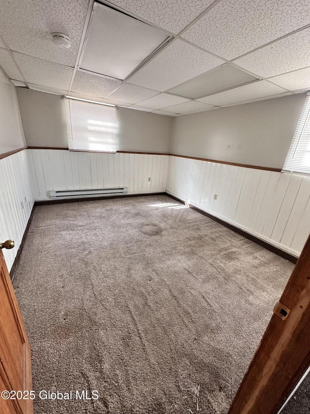 spare room featuring a wainscoted wall, a paneled ceiling, baseboard heating, and carpet flooring