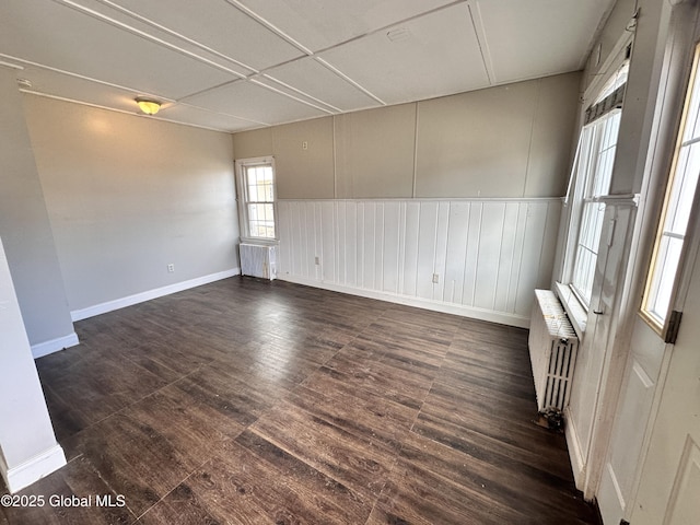 unfurnished room featuring baseboards, radiator, and dark wood-style flooring