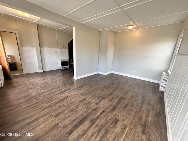 spare room with dark wood-style floors, heating unit, and baseboards