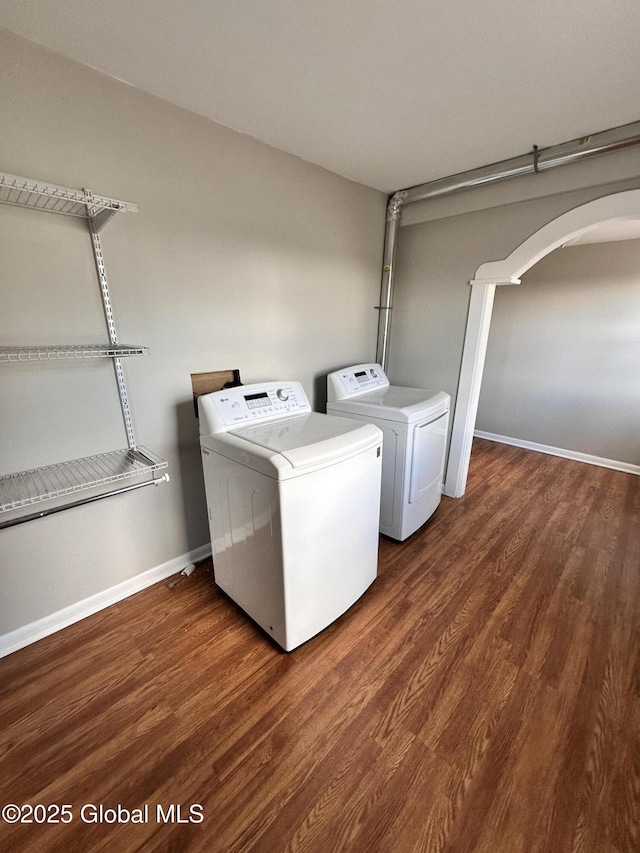 laundry area featuring wood finished floors, baseboards, laundry area, separate washer and dryer, and arched walkways