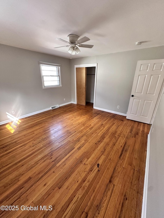 unfurnished bedroom with a ceiling fan, wood finished floors, visible vents, baseboards, and a closet