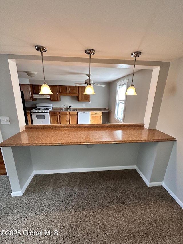 kitchen with a sink, under cabinet range hood, decorative light fixtures, white appliances, and baseboards