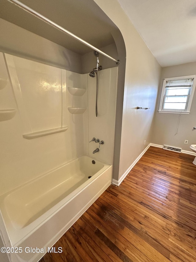 full bathroom with hardwood / wood-style flooring, baseboards, visible vents, and shower / washtub combination