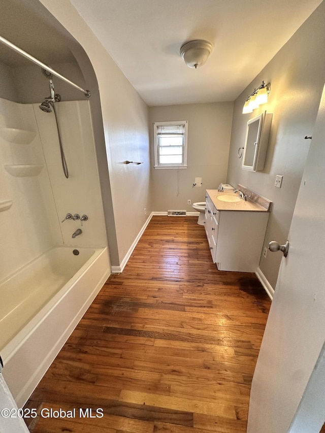 bathroom featuring toilet, vanity, baseboards, and wood finished floors