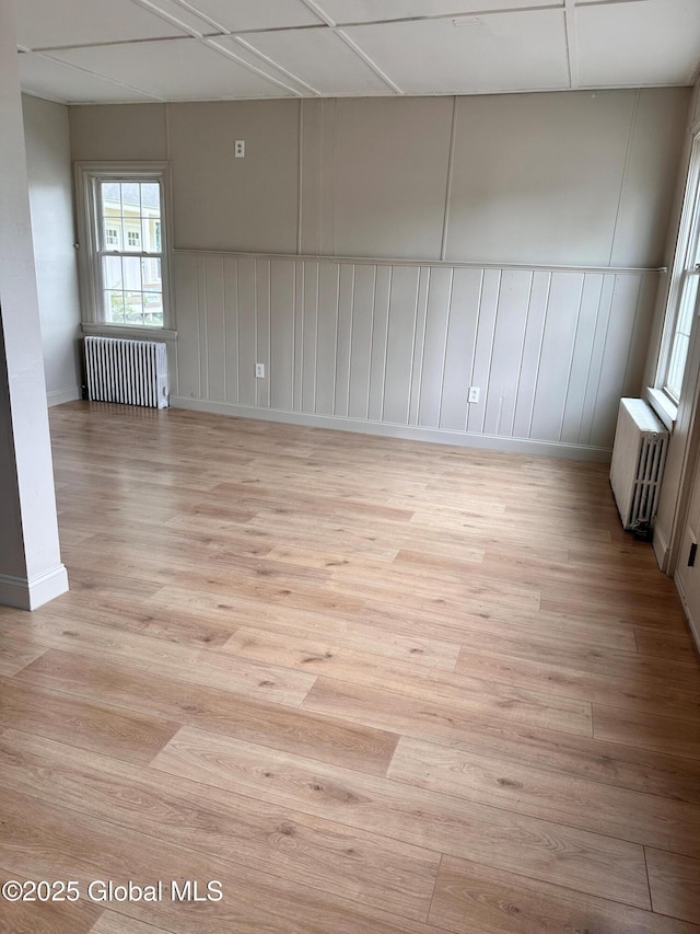1 S Main St, Voorheesville, NY 12186 - unfurnished room featuring radiator, light wood finished floors, and a decorative wall