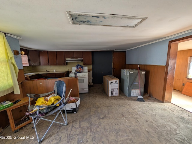 kitchen featuring wooden walls, white gas stove, under cabinet range hood, and wainscoting