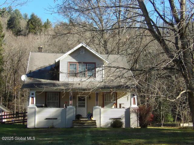 view of front facade featuring covered porch, a front lawn, and fence