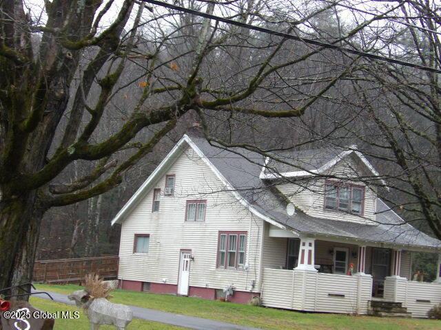 view of home's exterior featuring a yard, covered porch, and roof with shingles