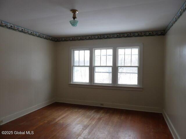 spare room featuring baseboards and wood finished floors