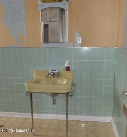 bathroom with a sink, a wainscoted wall, and tile walls