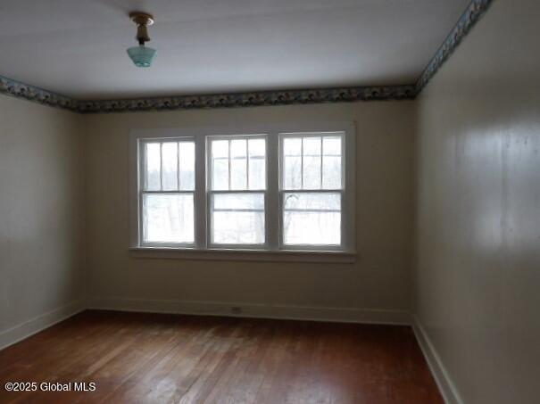 unfurnished room with wood finished floors and baseboards