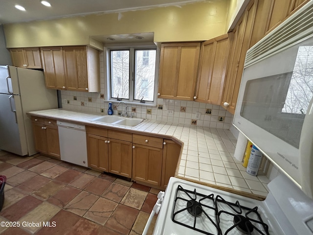 kitchen featuring brown cabinets, a sink, tasteful backsplash, tile countertops, and white appliances