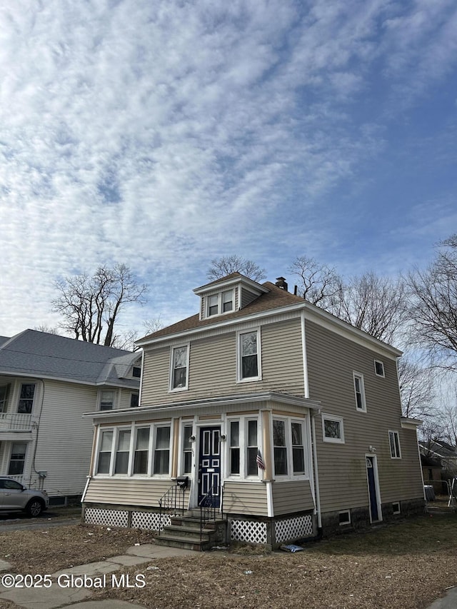 american foursquare style home with entry steps, a chimney, and a sunroom