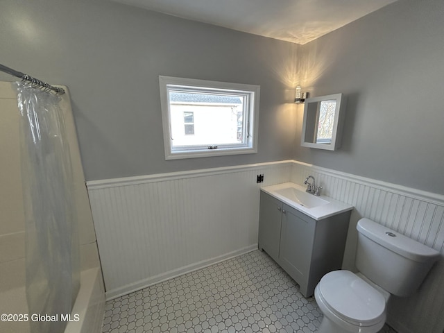 full bathroom with wainscoting, toilet, vanity, and shower / bathtub combination with curtain