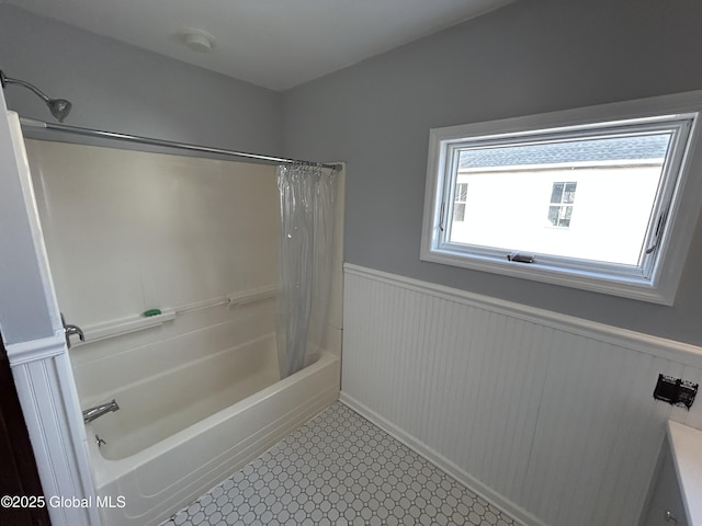 bathroom featuring wainscoting and shower / bath combination with curtain