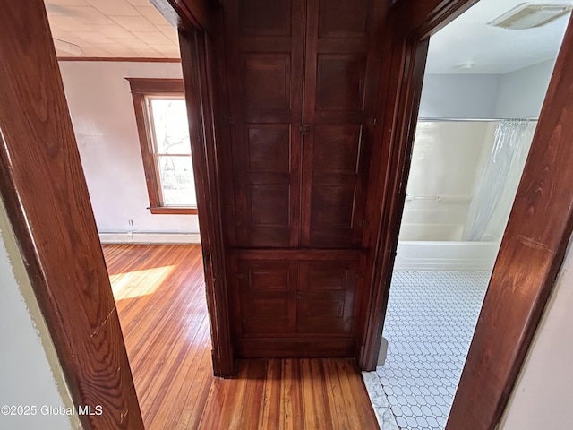 hall with visible vents, crown molding, and light wood-style floors