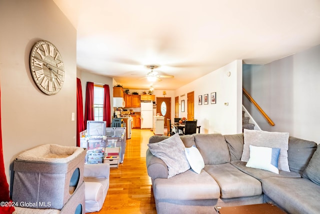 living room featuring ceiling fan, stairway, and light wood-style flooring