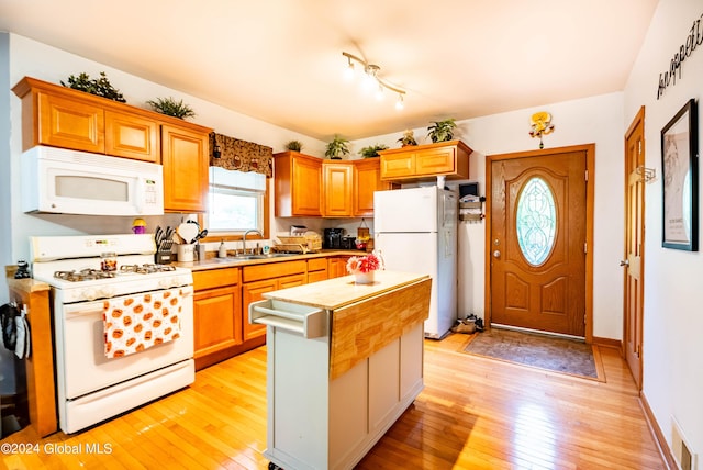 kitchen featuring light wood-type flooring, visible vents, a sink, white appliances, and light countertops