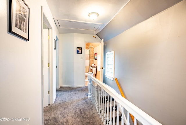 hallway featuring baseboards, attic access, lofted ceiling, an upstairs landing, and carpet flooring