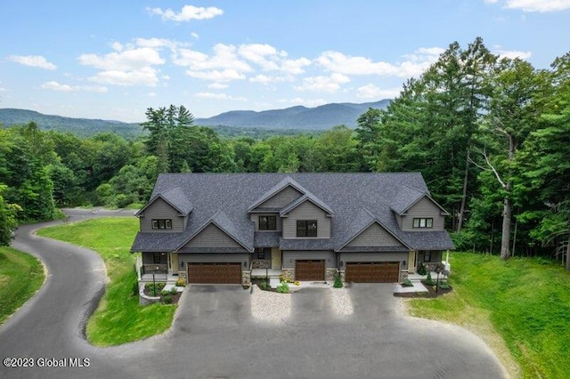 view of front of property with roof with shingles, a front lawn, stone siding, a view of trees, and a mountain view