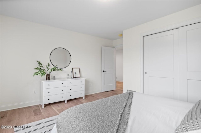 bedroom featuring baseboards, light wood-type flooring, and a closet