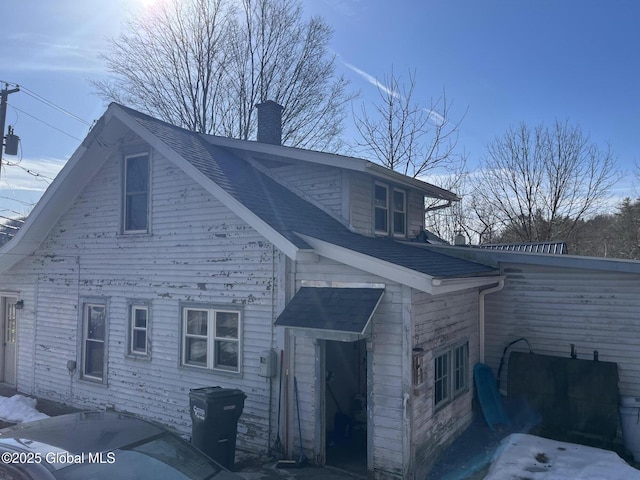 view of property exterior featuring a chimney and a shingled roof