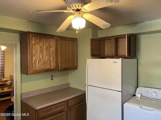 kitchen featuring washer / dryer, brown cabinetry, and freestanding refrigerator