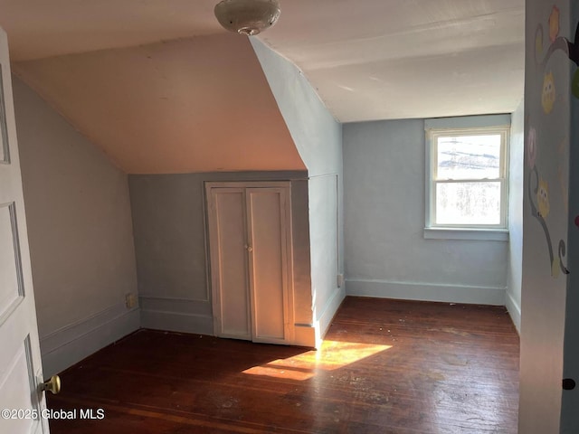 bonus room with baseboards, lofted ceiling, and dark wood-style flooring