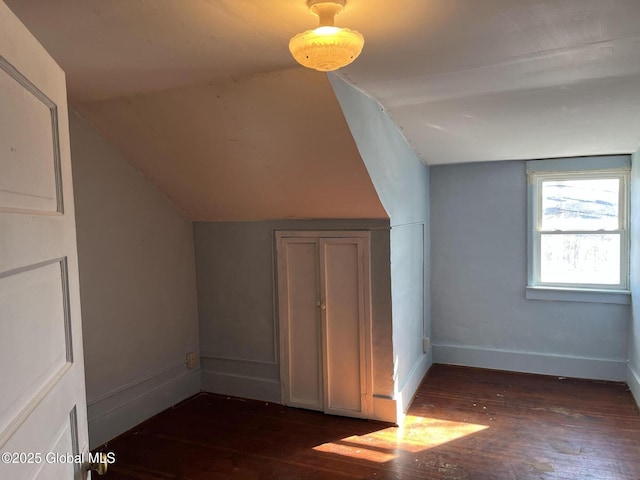 bonus room with dark wood finished floors, lofted ceiling, and baseboards