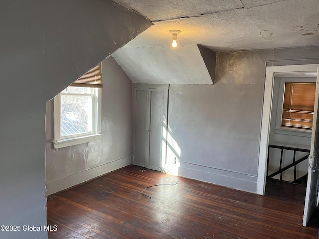 bonus room featuring vaulted ceiling, a textured ceiling, baseboards, and hardwood / wood-style flooring