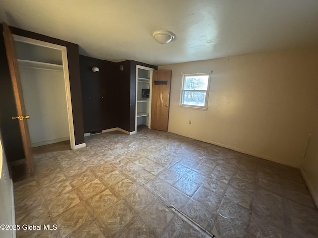 unfurnished bedroom with baseboards and multiple closets