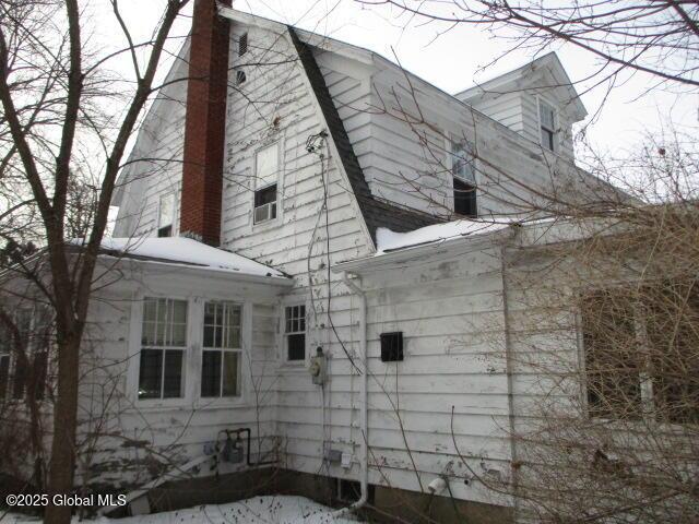 view of home's exterior with a gambrel roof and a chimney