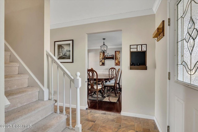 foyer with stone finish flooring, baseboards, ornamental molding, and stairs