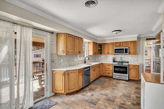 kitchen with visible vents, a sink, backsplash, stainless steel appliances, and crown molding