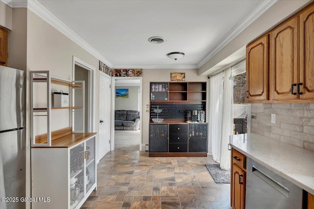 kitchen featuring tasteful backsplash, stone finish flooring, crown molding, light countertops, and appliances with stainless steel finishes