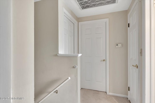 hall with light carpet, visible vents, and baseboards