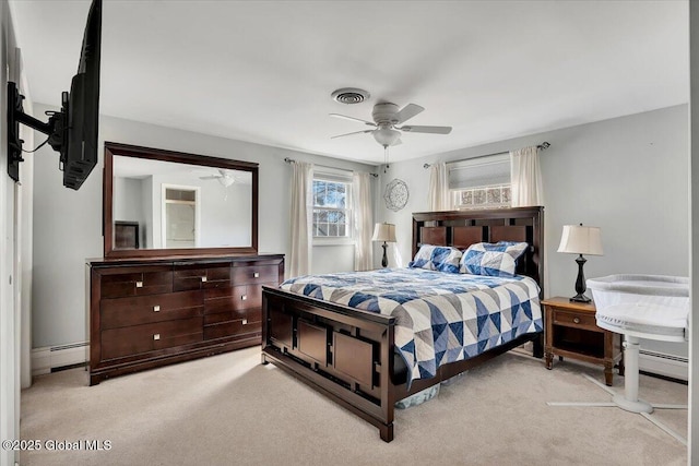 bedroom with baseboard heating, light colored carpet, visible vents, and ceiling fan