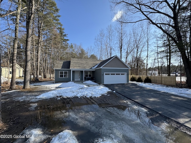 view of front of property featuring aphalt driveway, fence, and a garage