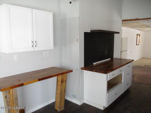 kitchen with white cabinetry, freestanding refrigerator, and butcher block countertops