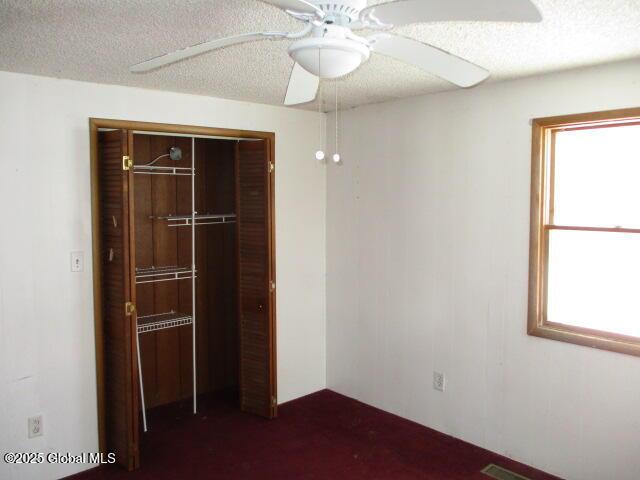 unfurnished bedroom featuring visible vents, a ceiling fan, a closet, and a textured ceiling