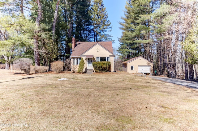 view of front facade featuring an outbuilding, a garage, a chimney, and a front lawn