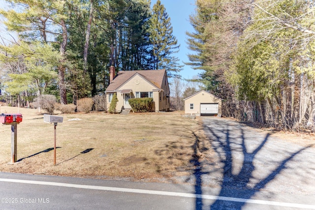 view of front of house with an outbuilding, a front lawn, driveway, a garage, and a chimney