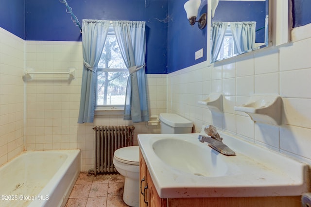 bathroom featuring toilet, a washtub, radiator, tile walls, and vanity