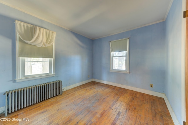 unfurnished room featuring hardwood / wood-style floors, baseboards, radiator, and ornamental molding